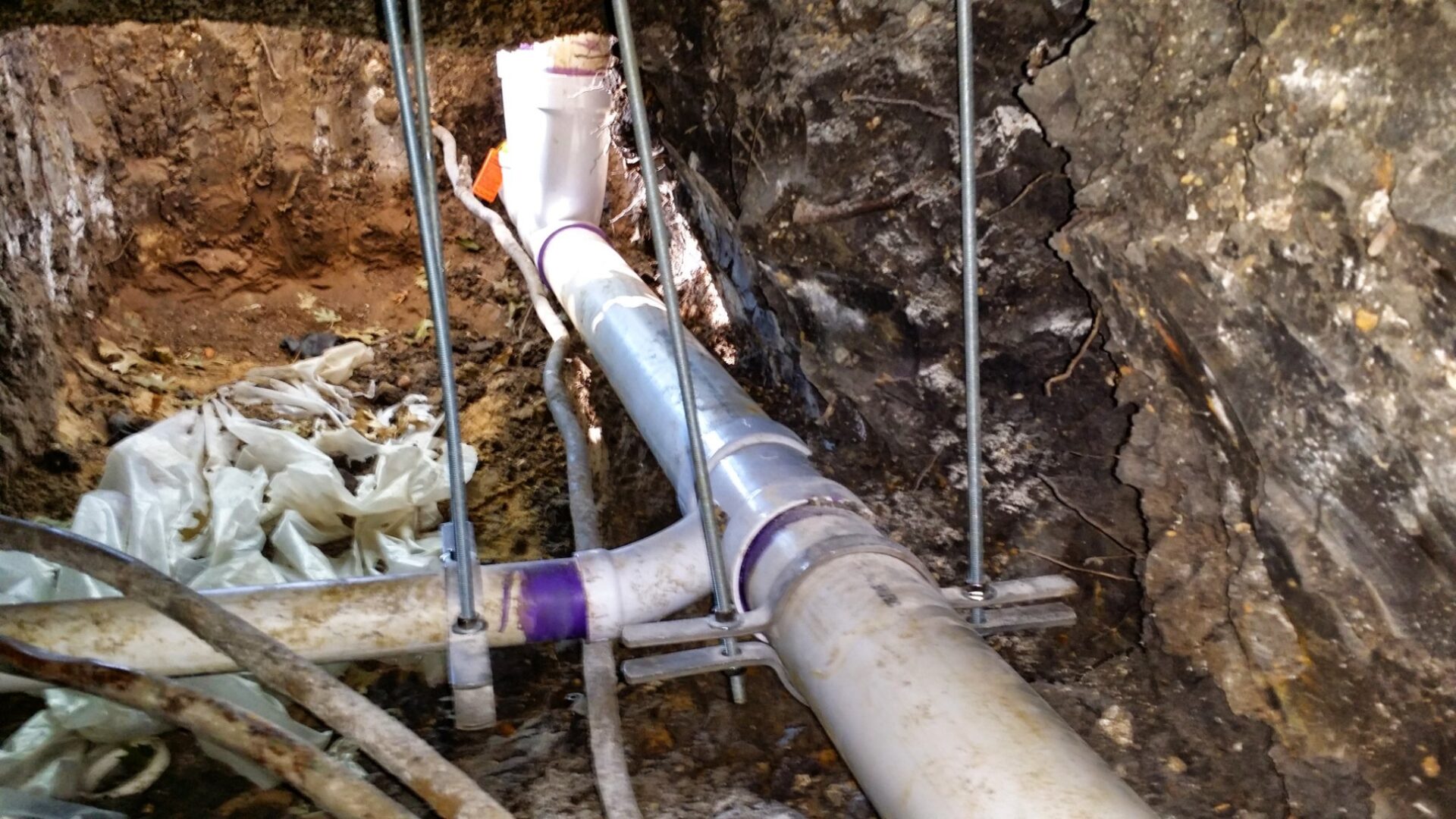 Exposed tunnel under a home's slab showing old drain pipes being replaced